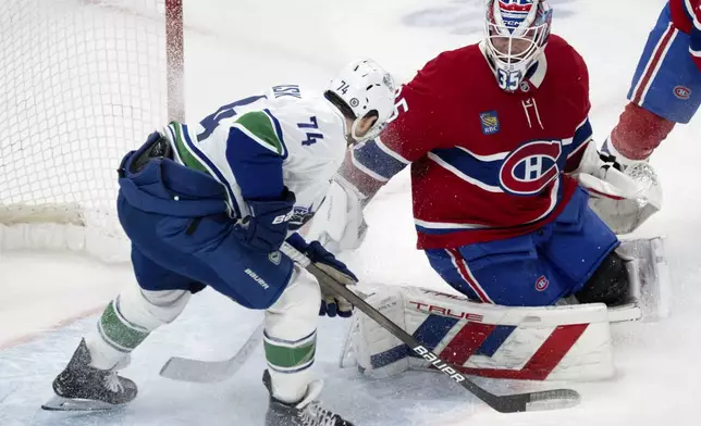 Montreal Canadiens goaltender Sam Montembeault (35) makes a save against Vancouver Canucks' Jake DeBrusk (74) during second-period NHL hockey game action in Montreal, Monday, Jan. 6, 2025. (Ryan Remiorz/The Canadian Press via AP)