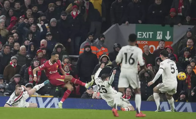 Liverpool's Cody Gakpo, left, scores his side's first goal against Manchester United during the English Premier League soccer match at the Anfield stadium in Liverpool, England, Sunday, Jan. 5, 2025. (AP Photo/Jon Super)