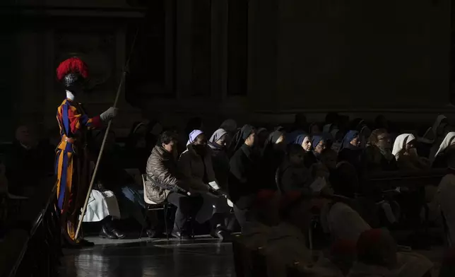 Faithful and a pontifical Swiss guard follow Pope Francis presiding over a mass in St. Peter's Basilica at The Vatican on New Year's Day, Wednesday, Jan. 1, 2025. (AP Photo/Andrew Medichini)