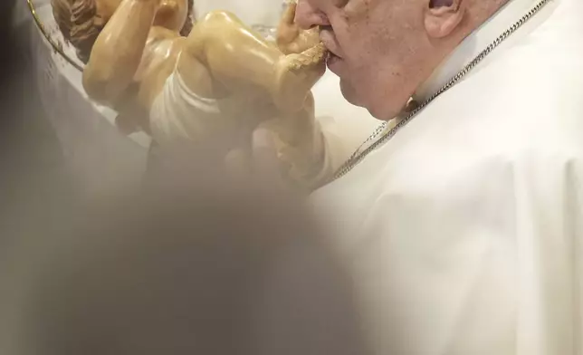 Pope Francis kisses a wooden statuette of the infant Jesus at the end of a mass in St. Peter's Basilica at The Vatican on New Year's Day, Wednesday, Jan. 1, 2025. (AP Photo/Andrew Medichini)