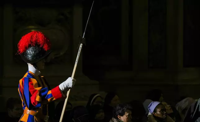 Faithful and a pontifical Swiss guard follow Pope Francis presiding over a mass in St. Peter's Basilica at The Vatican on New Year's Day, Wednesday, Jan. 1, 2025. (AP Photo/Andrew Medichini)