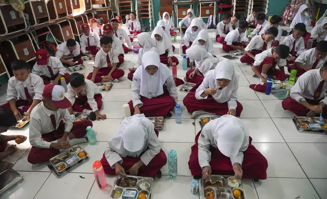 Students sit on the floor as they have their meals during the kick off of President Prabowo Subianto's ambitious free meal program to feed children and pregnant women nationwide despite critics saying that its required logistics could hurt Indonesia's state finances and economy, at an elementary school in Banten, Indonesia, Monday, Jan. 6, 2025. (AP Photo/Tatan Syuflana)