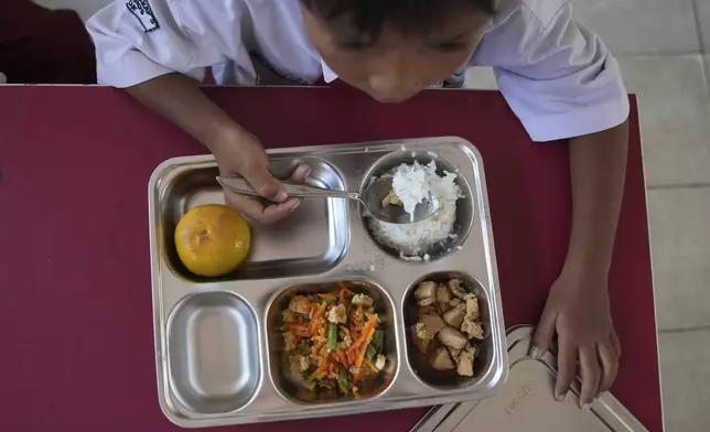 A student has his meal during the kick off of President Prabowo Subianto's ambitious free meal program to feed children and pregnant women nationwide despite critics saying that its required logistics could hurt Indonesia's state finances and economy, at an elementary school in Depok, West Java, Indonesia, Monday, Jan. 6, 2025. (AP Photo/Dita Alangkara)