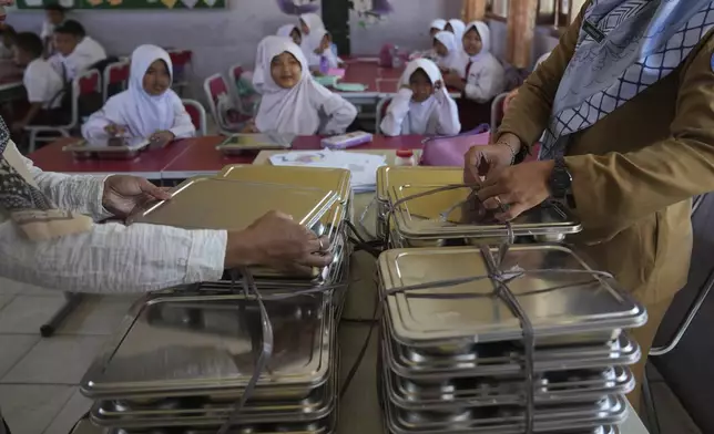 Teachers prepare meals for students during the kick off of President Prabowo Subianto's ambitious free meal program to feed children and pregnant women nationwide despite critics saying that its required logistics could hurt Indonesia's state finances and economy, at an elementary school in Depok, West Java, Indonesia, Monday, Jan. 6, 2025. (AP Photo/Dita Alangkara)