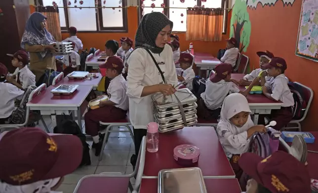 Members of school committee distribute meals to students during the kick off of President Prabowo Subianto's ambitious free meal program to feed children and pregnant women nationwide despite critics saying that its required logistics could hurt Indonesia's state finances and economy, at an elementary school in Depok, West Java, Indonesia, Monday, Jan. 6, 2025. (AP Photo/Dita Alangkara)