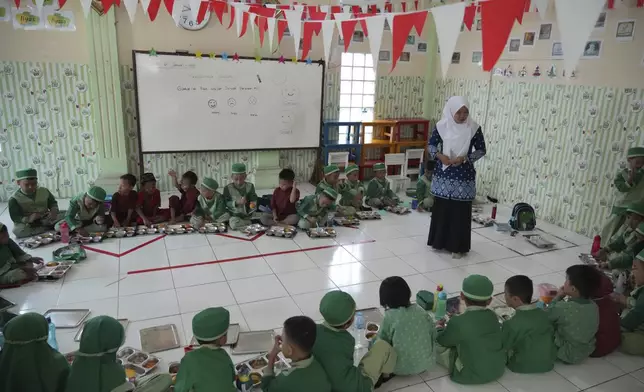 Students sit on the floor as they have their meals during the kick off of President Prabowo Subianto's ambitious free meal program to feed children and pregnant women nationwide despite critics saying that its required logistics could hurt Indonesia's state finances and economy at Early Childhood Education and Development in Jakarta, Indonesia, Monday, Jan. 6, 2025. (AP Photo/Achmad Ibrahim)