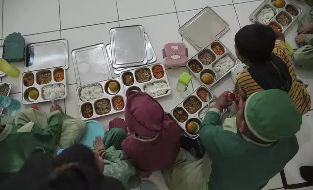 Students sit on the floor as they have their meals during the kick off of President Prabowo Subianto's ambitious free meal program to feed children and pregnant women nationwide despite critics saying that its required logistics could hurt Indonesia's state finances and economy at Early Childhood Education and Development in Jakarta, Indonesia, Monday, Jan. 6, 2025. (AP Photo/Achmad Ibrahim)