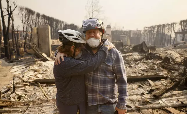 Claudio and Kathleen Boltiansky embrace in their fire-ravaged neighborhood after the Palisades Fire swept through in the Pacific Palisades neighborhood of Los Angeles, Wednesday, Jan. 8, 2025. (AP Photo/Etienne Laurent)