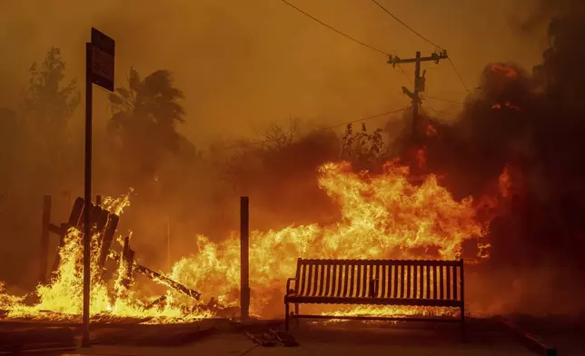 The Eaton Fire burns a bus stop Wednesday, Jan. 8, 2025 in Altadena, Calif. (AP Photo/Ethan Swope)