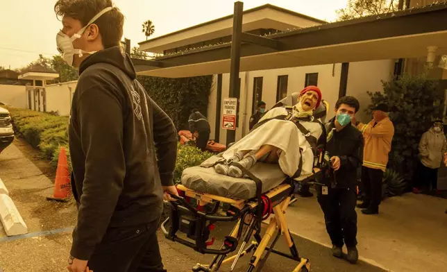 A resident is evacuated from a senior living facility as the Eaton Fire approaches Wednesday, Jan. 8, 2025 in Altadena, Calif. (AP Photo/Ethan Swope)