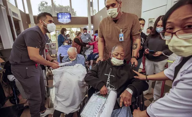 Residents are evacuated from a senior living facility as the Eaton Fire approaches Wednesday, Jan. 8, 2025 in Altadena, Calif. (AP Photo/Ethan Swope)