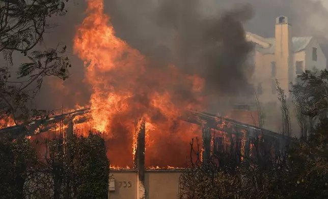 The Palisades Fire ravages a neighborhood amid high winds in the Pacific Palisades neighborhood of Los Angeles, Wednesday, Jan. 8, 2025. (AP Photo/Damian Dovarganes)