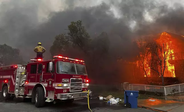 Firefighters battle the Palisades Fire as it burns structures in the Pacific Palisades neighborhood of Los Angeles, Wednesday, Jan. 8, 2025. (AP Photo/Eugene Garcia)