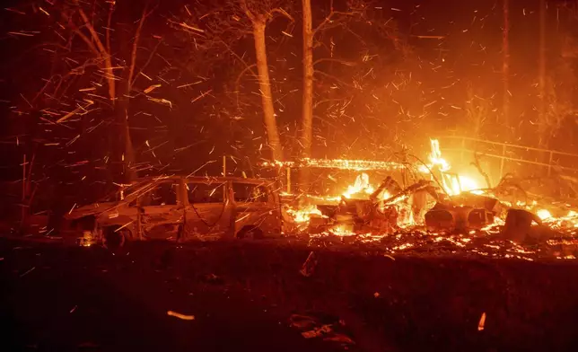 The Eaton Fire burns vehicles and structures Wednesday, Jan. 8, 2025 in Altadena, Calif. (AP Photo/Ethan Swope)