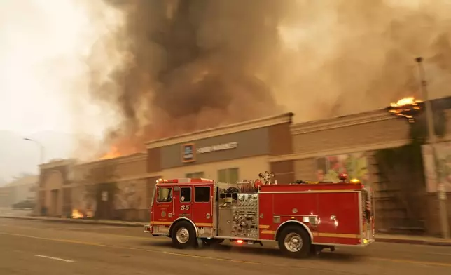 A fire truck speeds past a burning Aldi supermarket, Wednesday, Jan. 8, 2025, in the Altadena section of Pasadena, Calif. (AP Photo/Chris Pizzello)