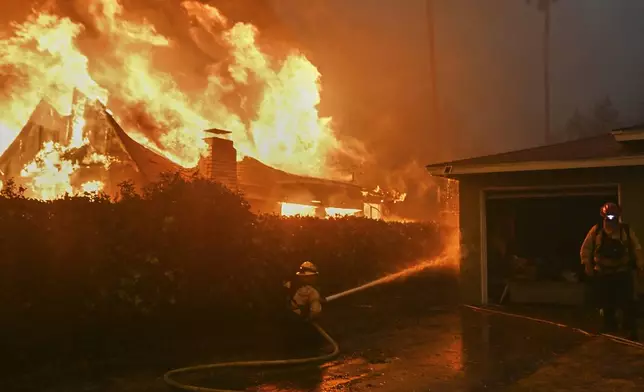 Fire crews battle the Eaton Fire next to a fully engulfed residence, Wednesday, Jan. 8, 2025 in Altadena, Calif. (AP Photo/Nic Coury)