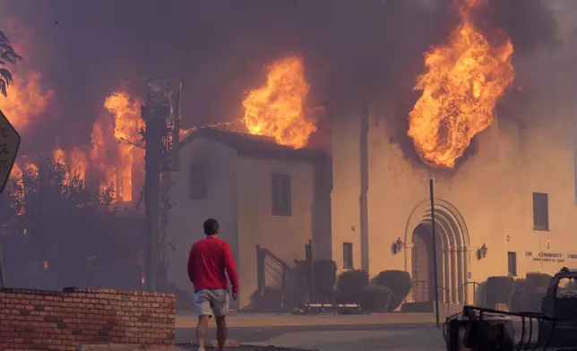 A man walks in front of the burning Altadena Community Church, Wednesday, Jan. 8, 2025, in in Pasadena, Calif. (AP Photo/Chris Pizzello)