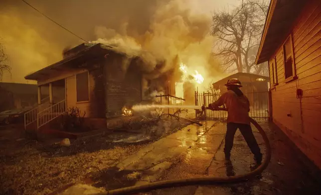 A firefighter battles the Eaton Fire Wednesday, Jan. 8, 2025 in Altadena, Calif. (AP Photo/Ethan Swope)