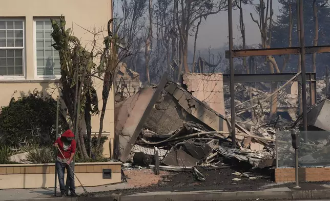 A person begins cleaning up after the Palisades Fire ravaged a neighborhood amid high winds in the Pacific Palisades neighborhood of Los Angeles, Wednesday, Jan. 8, 2025. (AP Photo/Damian Dovarganes)