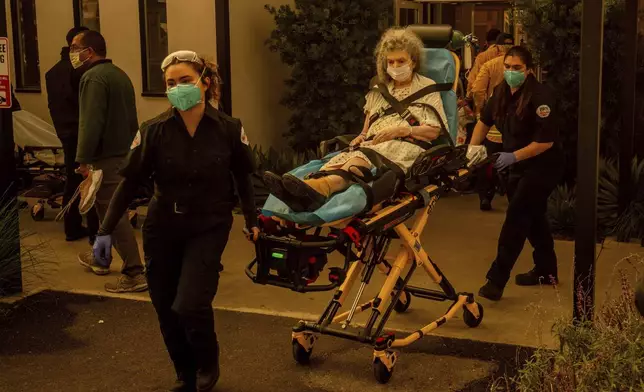 A resident is evacuated from a senior living facility as the Eaton Fire approaches Wednesday, Jan. 8, 2025, in Altadena, Calif. (AP Photo/Ethan Swope)