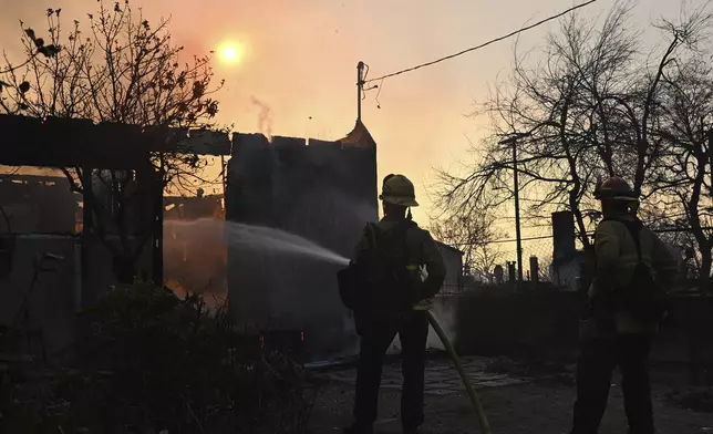 Firefighters water down a home after the Eaton Fire burns in Altadena, Calif., Thursday, Jan. 9, 2025. (AP Photo/Nic Coury)