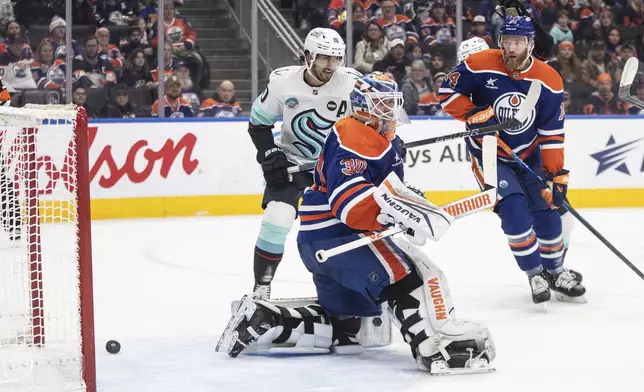 Seattle Kraken's Matty Beniers (10) and Edmonton Oilers' Mattias Ekholm (14) watch as the puck goes into the net past Oilers goalie Calvin Pickard (30) during first-period NHL hockey game action in Edmonton, Alberta, Monday, Jan. 27, 2025. (Jason Franson/The Canadian Press via AP)