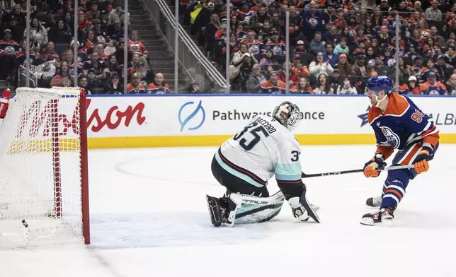 Seattle Kraken goalie Joey Daccord (35) is scored against by Edmonton Oilers' Corey Perry (90) during second-period NHL hockey game action in Edmonton, Alberta, Monday, Jan. 27, 2025. (Jason Franson/The Canadian Press via AP)