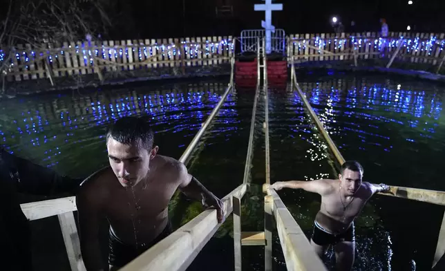 Men exit a pond after plunging themselves in icy waters to celebrate the Orthodox Epiphany at the Izmailovsky Kremlin in Moscow, Russia, Saturday, Jan. 18, 2025. (AP Photo/Pavel Bednyakov)