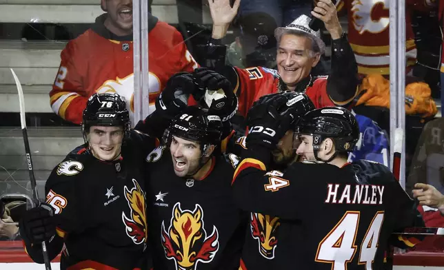Calgary Flames' Nazem Kadri (91) celebrates after his goal with teammates during the third period of an NHL hockey game against the Vancouver Canucks in Calgary, Alberta, Tuesday, Dec. 31, 2024. (Jeff McIntosh/The Canadian Press via AP)