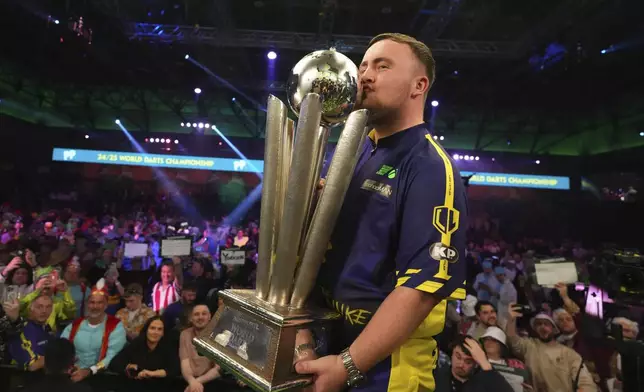 Luke Littler of England kisses the trophy after winning the final against Michael van Gerwen of the Netherlands at the World Darts Championship at Alexandra Palace in London, Friday, Jan. 3, 2025. (AP Photo/Kirsty Wigglesworth)