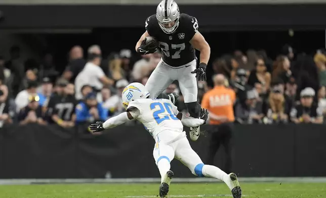 Las Vegas Raiders tight end Michael Mayer (87) is tackled by Los Angeles Chargers cornerback Cam Hart (20) during the first half of an NFL football game in Las Vegas, Sunday, Jan. 5, 2025. (AP Photo/Abbie Parr)