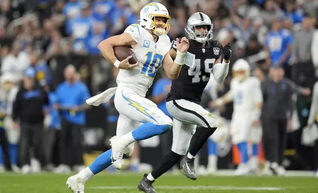 Los Angeles Chargers quarterback Justin Herbert (10) runs against Las Vegas Raiders defensive end Charles Snowden (49) during the second half of an NFL football game in Las Vegas, Sunday, Jan. 5, 2025. (AP Photo/Abbie Parr)