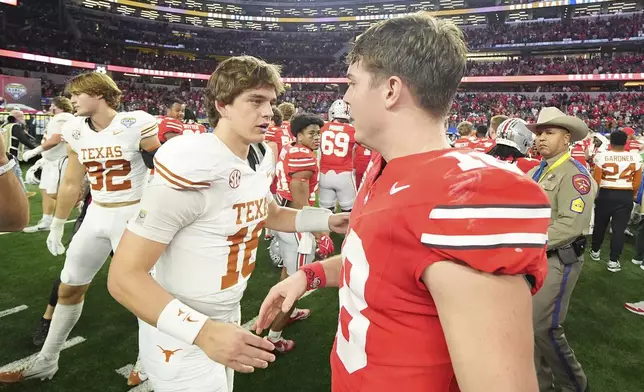 Texas quarterback Arch Manning, middle left, shakes hands with Ohio State quarterback Will Howard after the Cotton Bowl College Football Playoff semifinal game, Friday, Jan. 10, 2025, in Arlington, Texas. (AP Photo/Julio Cortez)