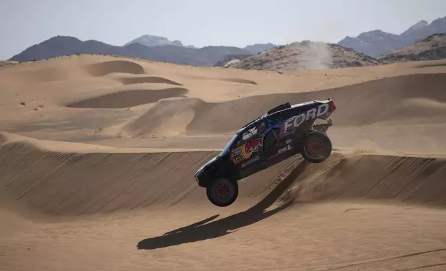 Driver Carlos Sainz and co-driver Lucas Cruz compete during the stage two, day One, of the Dakar Rally with start in Bisha and finish in Bisha, Saudi Arabia, Sunday, Jan. 5, 2025. (AP Photo/Christophe Ena)