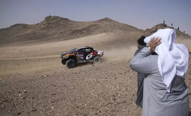 People watch driver Henk Lategan and co-driver Brett Cummings during the prologue of the Dakar Rally in Bisha, Saudi Arabia, Friday, Jan. 3, 2025. (AP Photo/Christophe Ena)