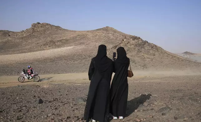 Women take photos of Andrea Winkler of Italy as he rides during the prologue of the Dakar Rally in Bisha, Saudi Arabia, Friday, Jan. 3, 2025. (AP Photo/Christophe Ena)