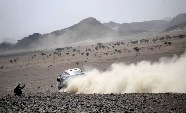 A man takes a photo of a car during the prologue of the Dakar Rally in Bisha, Saudi Arabia, Friday, Jan. 3, 2025. (AP Photo/Christophe Ena)