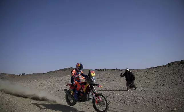 A man takes a photo of Luciano Benavides of Argentina as he rides during the prologue of the Dakar Rally in Bisha, Saudi Arabia, Friday, Jan. 3, 2025. (AP Photo/Christophe Ena)