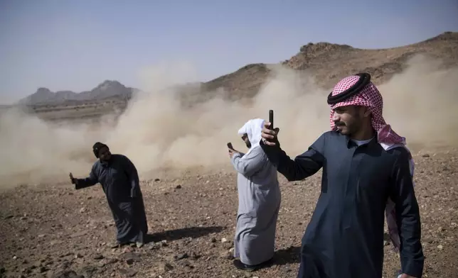 People take photos of drivers during the prologue of the Dakar Rally in Bisha, Saudi Arabia, Friday, Jan. 3, 2025. (AP Photo/Christophe Ena)