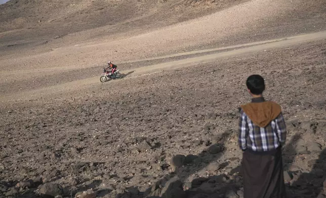 A young boy watches riders during the prologue of the Dakar Rally in Bisha, Saudi Arabia, Friday, Jan. 3, 2025. (AP Photo/Christophe Ena)