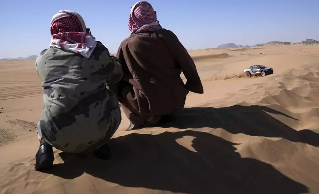 Two men take photos of Driver Mattias Ekstrom and co-driver Emil Bergkvist during the stage two, day One, of the Dakar Rally with start in Bisha and finish in Bisha, Saudi Arabia, Sunday, Jan. 5, 2025. (AP Photo/Christophe Ena)