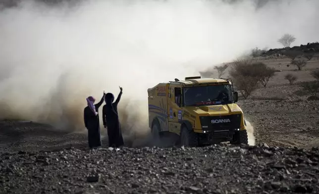 Young boys wave Truck driver Miklos Kovacs and co-drivers Laszlo Acs and Peter Czegledi as they compete during the prologue of the Dakar Rally in Bisha, Saudi Arabia, Friday, Jan. 3, 2025. (AP Photo/Christophe Ena)