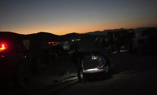 Ford driver Nani Roma of Spain repairs a wheel at the bivouac after the stage two, day one, of the Dakar Rally with start in Bisha and finish in Bisha, Saudi Arabia, Sunday, Jan. 5, 2025. (AP Photo/Christophe Ena)