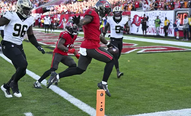 Tampa Bay Buccaneers running back Bucky Irving scores a touchdown between New Orleans Saints defensive end Carl Granderson (96) and cornerback Will Harris (5) during the second half of an NFL football game Sunday, Jan. 5, 2025, in Tampa, Fla. The Buccaneers won 27-19. (AP Photo/Jason Behnken)