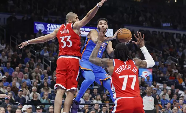 Oklahoma City Thunder forward Kenrich Williams, center, looks to pass the ball away from Los Angeles Clippers forward Nicolas Batum (33) and guard Kevin Porter Jr. (77) during the first half of an NBA basketball game Thursday, Jan. 2, 2025, in Oklahoma City. (AP Photo/Nate Billings)