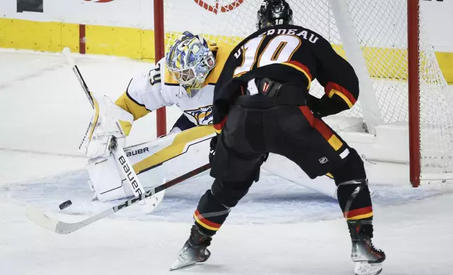 Nashville Predators goalie Justus Annunen, left, kicks away a shot from Calgary Flames' Jonathan Huberdeau during the second period of an NHL hockey game in Calgary, Alberta, Saturday, Jan. 4, 2025. (Jeff McIntosh/The Canadian Press via AP)