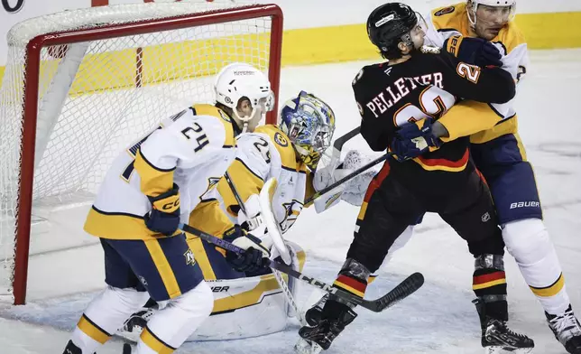 Nashville Predators' Luke Schenn, right, checks Calgary Flames' Jakob Pelletier, second right, as Spencer Stastney, left, and goalie Justus Annunen look on during the first period of an NHL hockey game in Calgary, Alberta, Saturday, Jan. 4, 2025. (Jeff McIntosh/The Canadian Press via AP)