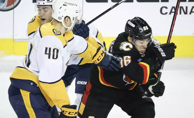 Nashville Predators' Fedor Svechkov, center, and Mark Jankowski, left, check Calgary Flames' Andrei Kuzmenko during the second period of an NHL hockey game in Calgary, Alberta, Saturday, Jan. 4, 2025. (Jeff McIntosh/The Canadian Press via AP)