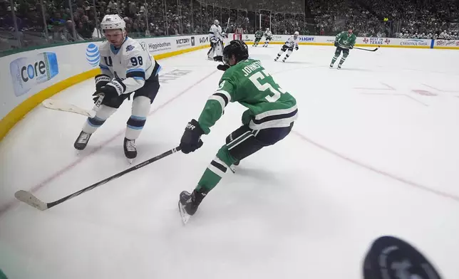 Utah Hockey Club defenseman Mikhail Sergachev (98) clears the puck away as Dallas Stars center Wyatt Johnston (53) attacks during the first period of an NHL hockey game, Saturday, Jan. 4, 2025, in Dallas. (AP Photo/Julio Cortez)