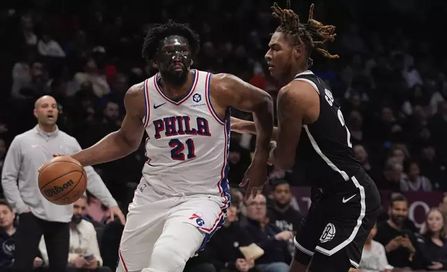 Philadelphia 76ers' Joel Embiid (21) drives past Brooklyn Nets' Jalen Wilson (22) during the second half of an NBA basketball game Saturday, Jan. 4, 2025, in New York. (AP Photo/Frank Franklin II)